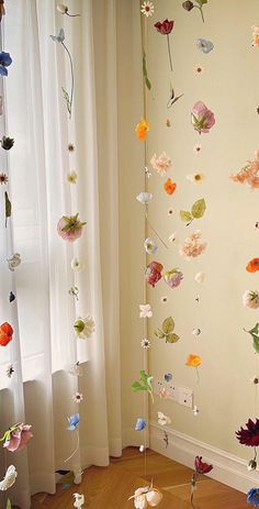 a room with flowers hanging from the ceiling and curtains on the window sill behind it