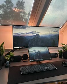 a computer monitor sitting on top of a desk next to a keyboard and mouse in front of a window