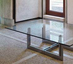 a glass table sitting on top of a floor next to a window in a room