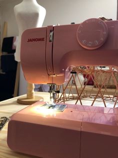 a pink sewing machine sitting on top of a wooden table next to a white mannequin