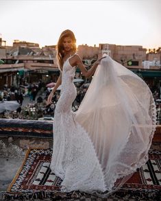 a woman in a white wedding dress is standing on a rug with her veil over her head