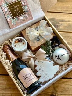 an open gift box with wine, cookies and other items in it on a wooden table