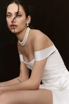 a woman in a white dress sitting on the ground