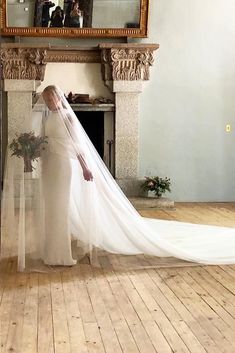 a woman in a wedding dress standing next to a fireplace