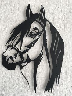 a metal horse head mounted to the side of a white wall with black paint on it