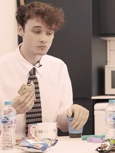 a man sitting at a table with food in his hands and water bottles around him