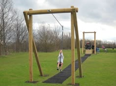 a person on a rope swing in the grass with people watching from behind it and an overhead trampoline