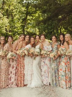 a group of women standing next to each other wearing dresses and holding bouquets in their hands