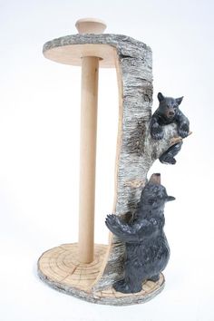 two bears are climbing up the side of a tree stump with a cat scratching post