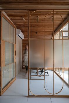 an office with wooden walls and glass partitions in the center, while a person walks by