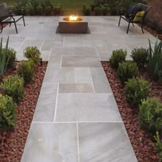 an outdoor fire pit surrounded by plants and rocks