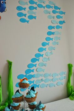 a table topped with cupcakes covered in blue frosting next to a wall