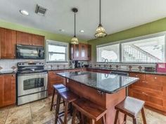 a kitchen with an island, stove and sink in it's center area next to two stools