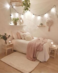 a bedroom with white walls and wooden flooring, lights strung from the ceiling over the bed