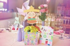 a table with flowers, cards and decorations on it in front of a pink background