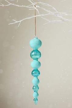 a glass ornament hanging from a tree branch with snow falling on the ground