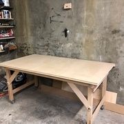 a workbench in a garage with tools on the floor and shelves behind it