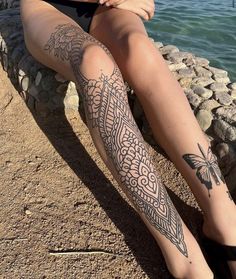 a woman is sitting on a stone bench with her legs crossed and tattoos on the leg