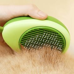 a close up of a person's hand holding a brush on top of dry grass