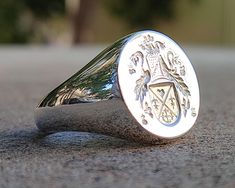 "Welcome to our online store, where we specialize in crafting beautiful and unique \"Family Crest Rings\" and \"Coat of Arms Rings\". Our rings are expertly crafted using only the finest materials, including premium gold and silver, and adorned with exquisite gemstones, such as emeralds, rubies, sapphires, onyx, aquamarine, and lapis. At our store, we take pride in offering a customization service where our skilled artisans will carve your family crest or coat of arms onto the ring, creating a stunning and detailed piece that is unique to your family. Our rings are more than just a beautiful accessory, they are also a meaningful family heirloom that will be cherished for generations to come. The tradition of family crests and coats of arms dates back centuries, symbolizing the rich history Luxury Engraved Ring With Coat Of Arms For Anniversary, Luxury Engraved Ring With Coat Of Arms As Gift, Luxury Engraved Ring With Coat Of Arms For Gift, Luxury Engraved Coat Of Arms Ring As Gift, Luxury Engraved Ring With Coat Of Arms, Gift Signet Ring With Coat Of Arms, Anniversary Coat Of Arms Signet Ring, Signet Ring Family Crest, Latimer Coat Of Arms Ring