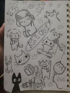 someone is holding up a notebook with some drawings on it, including cats and dogs