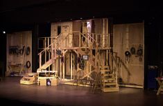 the stage is set up for a play with lots of wooden furniture and stairs on it