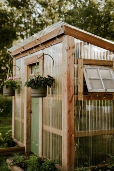 a small wooden greenhouse with plants growing in the roof and windows on it's sides