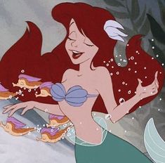 ariel from the little mermaid with her hair blowing in the wind and holding two fish