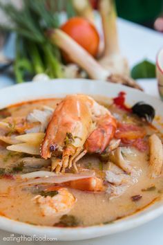 a white plate topped with soup and shrimp