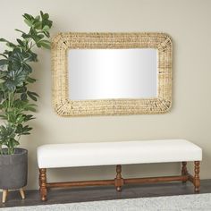 a white bench sitting next to a mirror and potted plant on top of a rug