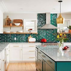 a kitchen with white cabinets and green tiles on the backsplash, counter tops