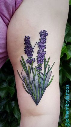 a woman's thigh with purple flowers on her left side and green leaves in the background