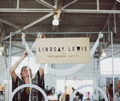 a woman holding up a sign in front of a computer screen with the words lindsey lewis on it