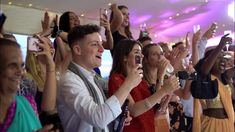 a group of people taking pictures with their cell phones in front of an audience at a party