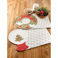 two quilted placemats sitting on top of a wooden floor next to a potted plant