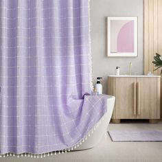 a bathroom with a bathtub, sink and purple shower curtain in the middle of it