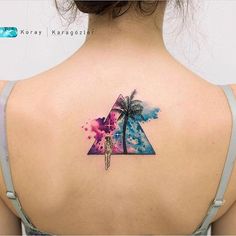 the back of a woman's shoulder with a colorful triangle and palm tree tattoo on it