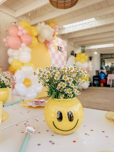 a yellow vase with daisies in it sitting on a table next to other decorations