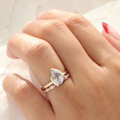 a woman's hand holding a ring with a pear shaped diamond on it and the words stacking idea written below