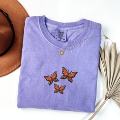 Comfort Colors Butterflies T-Shirt, Embroidered Butterflies Shirt, Cute Butterfly Shirt, Embroidered Insect T-shirt, Custom Butterfly Shirt This embroidered butterflies shirt is everything. Perfect to wear to show your love for butterflies! Please let me know if you are interested in a size 4X, I have certain size and color options available! ✨ 100% Cotton ✨ Pre-shrunk ✨ Relaxed fit Care: Machine wash: warm (max 40C or 105F) Tumble dry: low Do not iron directly on the design REFUNDS AND EXCHANGE Short Sleeve Cotton Tops With Butterfly Embroidery, Casual Purple Tops With Embroidered Graphics, Spring Crew Neck T-shirt With Butterfly Embroidery, Spring Butterfly Embroidered Crew Neck T-shirt, Embroidered Butterflies, Butterfly Shirt, Butterfly Shirts, Embroidered Butterfly, Cute Butterfly