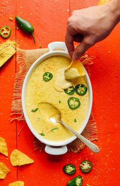 a person dipping tortilla chips into a bowl of quesadilla soup