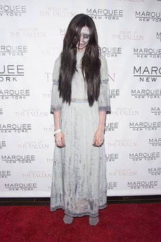 a woman with makeup on her face standing in front of a marquee poster