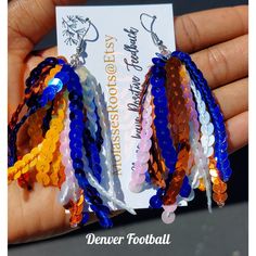 We at Molasseshoops Pride Ourselves On Designing & Finding Affordable Unique High-Quality Fashion Products. We Design For All Of Mankind!! 🌍 ⚠️ WARNING OUR PICTURES DON'T JUSTIFY THE SPARKLE IN THESE CELEBRATION BEAUTIES⚠️ Introducing Our Newest Denver Football Celebration Custom Earrings These Sequin Beauties Are Full Of Layers Yet Extremely Lightweight, Eye Catching & Flowly AVAILABLE IN 2 DANGLE SIZES: *SHORTIES: 2.4 INCHES (Ear Lobe To Jaw Line) *LONG: 4.6 INCHES (Ear Lobe to Above Mid-Neck Football Accessories Ideas, Diy Sequin Earrings, Yarn Earrings Diy, Football Celebrations, Sequin Earrings, Football Earrings, Jaw Line, Polymer Clay Jewelry Diy, Clay Jewelry Diy