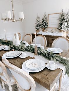 the table is set for christmas dinner with candles and greenery on it's side