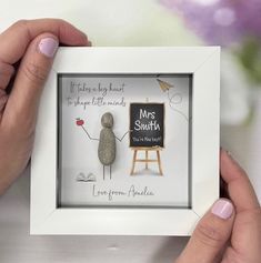 two hands holding up a framed photo with a rock in the shape of a man's hand