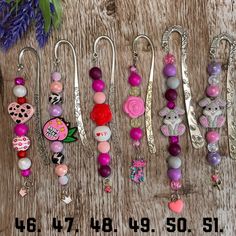 a bunch of different colored beads and charms on a wooden table next to purple flowers