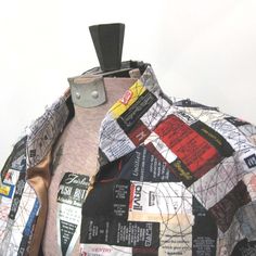 a man's jacket covered in many different types of paper and tags on it