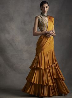 A vibrant pre-stitched layered saree with an embroidered cutwork belt. The saree is paired with a pearl, sequins, tilla & mirror work hand embroidered blouse. The sleeves have pearl & sikka... Luxury Pre-draped Saree With Mirror Work For Diwali, Luxury Traditional Wedding Dress With Drape, Luxury Yellow Bollywood Pre-draped Saree, Luxury Bollywood Pre-draped Yellow Saree, Luxury Bollywood Yellow Pre-draped Saree, Luxury Traditional Saree With Latkans, Drape Lehenga, Bhumika Sharma, Drape Saree