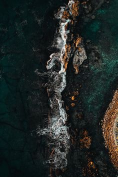 an aerial view of the ocean with waves crashing against the rocks and water flowing over it