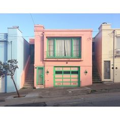 a pink house with green doors and windows